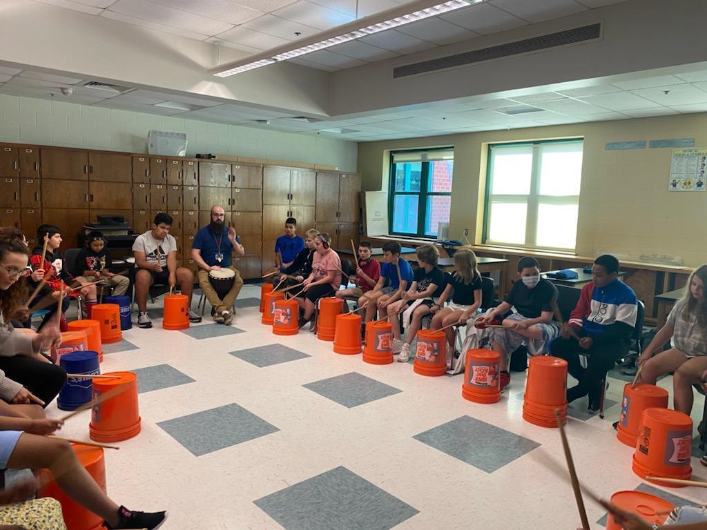 Students drumming on 5 gallon buckets
